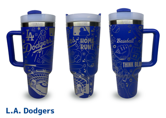 A set of three blue 40oz engraved tumblers featuring a Los Angeles Dodgers baseball theme. The tumblers have intricate silver engravings, including the "Dodgers" logo, baseball-related illustrations such as a stadium, bats, gloves, and players, along with phrases like "Home Run!" and "Think Blue." Each tumbler has a handle, a clear lid, and stainless steel accents. The background is plain white, and "L.A. Dodgers" is written in bold blue text below the image.
